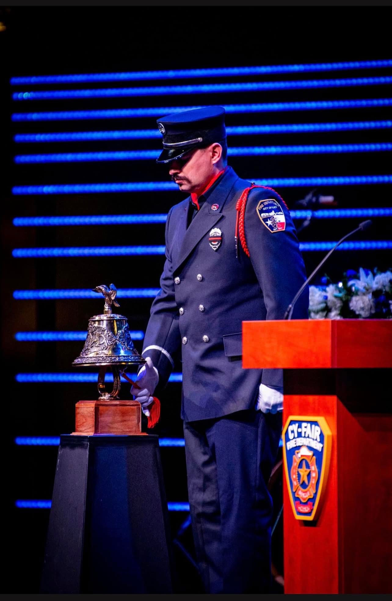 A Katy Honor Guard member standing beside a ceremonial bell at a remembrance program